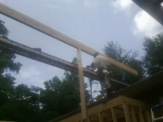 Carpenter setting a ridge beam over a new addition frame — Ice Dam Removal by Roofing Brothers in Bailey