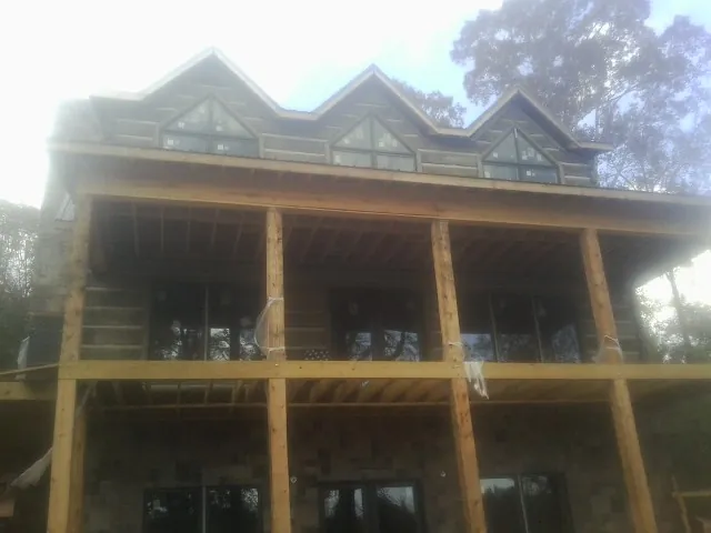 Dormers and porch framing on a large log home under construction — Roof Coating work by our crew in Bailey